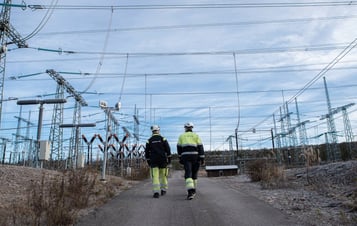 Två Vattenfall-medarbetare som går under kraftledningar i Harsprånget Två Vattenfall-medarbetare som går under kraftledningar i Harsprånget