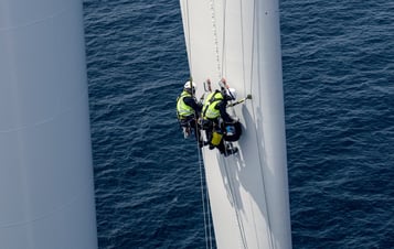 Tekniker i säkerhetskläder klättrar på ett rotorblad till en vindturbin Tekniker i säkerhetskläder klättrar på ett rotorblad till en vindturbin